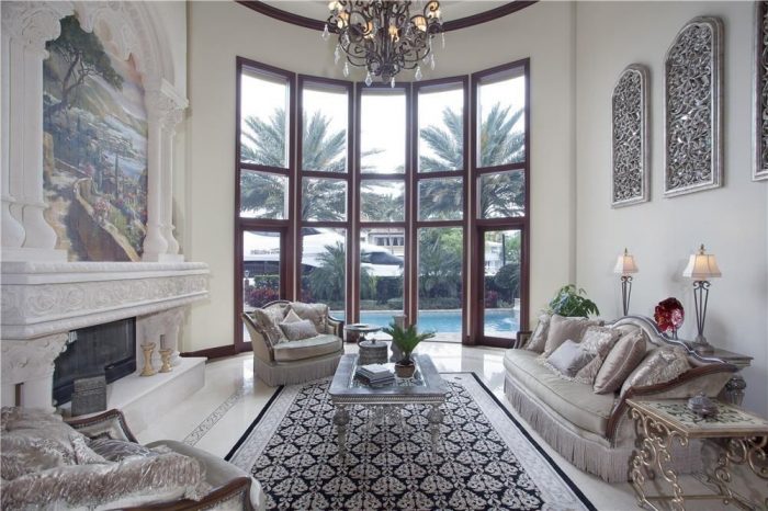 An ornate Mediterranean-style living room with large windows and a fireplace.