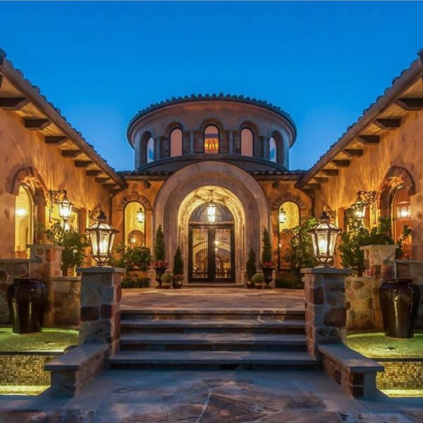 The entrance to a luxurious Mediterranean style home at dusk.