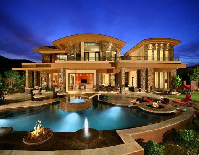 A luxurious home with a pool at night.