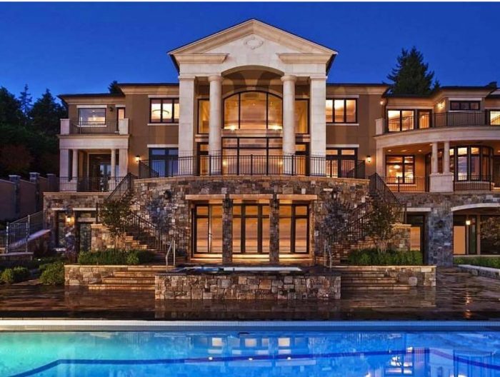 A lavish mansion with a pool illuminated at night.