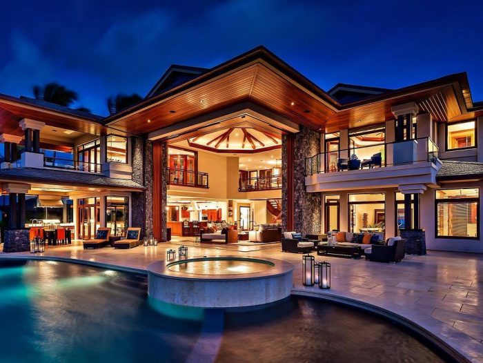 A luxurious house with a pool at night.