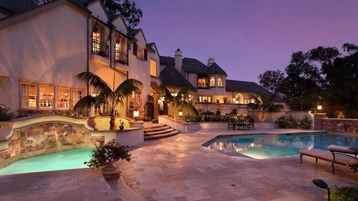 A luxurious home with a pool and patio at dusk.