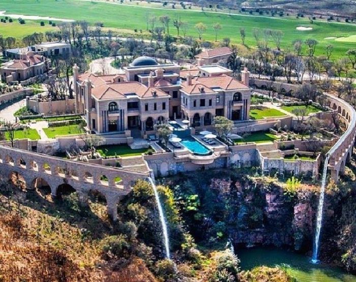 A luxurious mansion with a waterfall as seen from above.