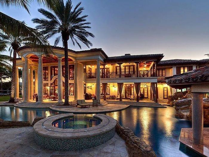 A luxurious mansion with a pool and palm trees.
