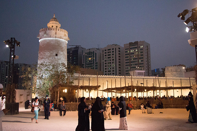 A group of people standing in front of a clock tower in Abu Dhabi.