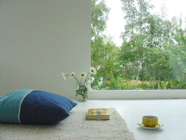 A Norwegian home with a white room, a blue pillow, and a cup of coffee.