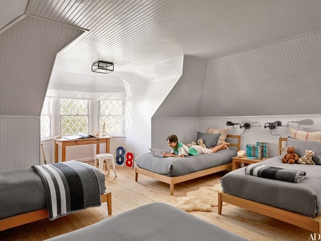 A child's bedroom with two beds and a desk.