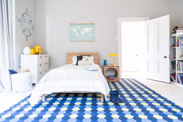 A child's room with a blue and yellow rug.