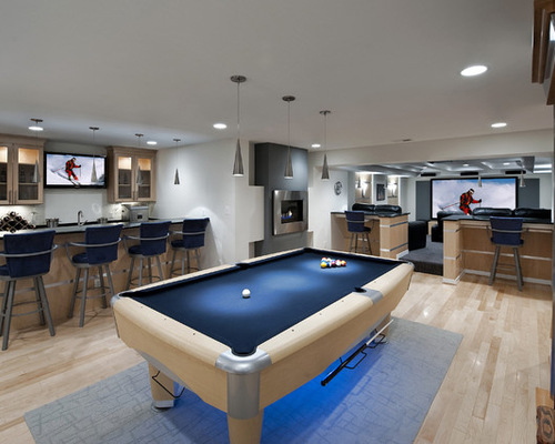 A windowless game room with a pool table and bar stools.