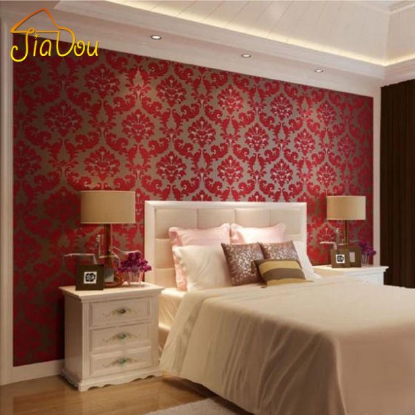 A bedroom with textured red and brown wallpaper.