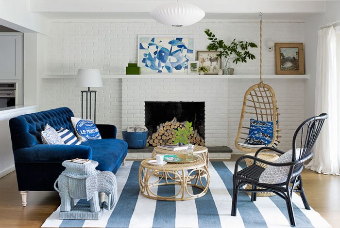 A living room with a denim blue couch and striped rug.