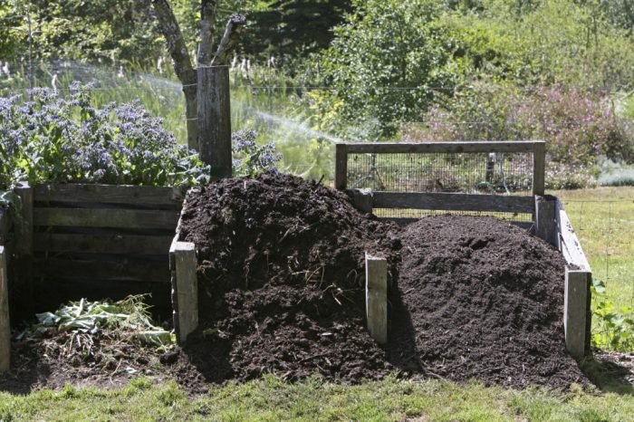 A compost bin contains a pile of dirt in a garden.