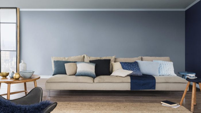 A living room with denim blue walls and a beige couch.