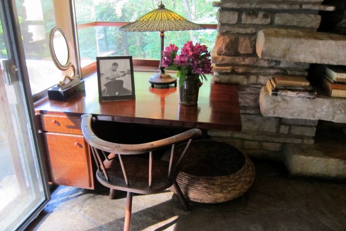 A desk in a room with a fireplace designed by Frank Lloyd Wright.