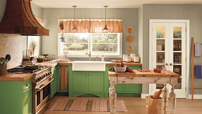 A kitchen with Pantone's green cabinets and a wooden table.