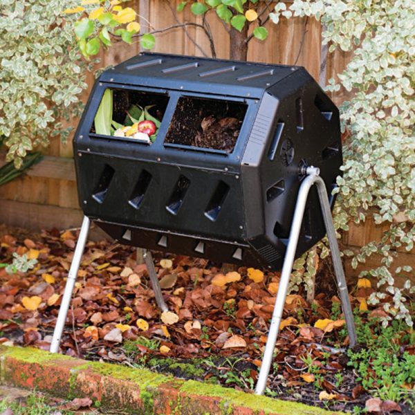 A black composter in a garden is used for composting.
