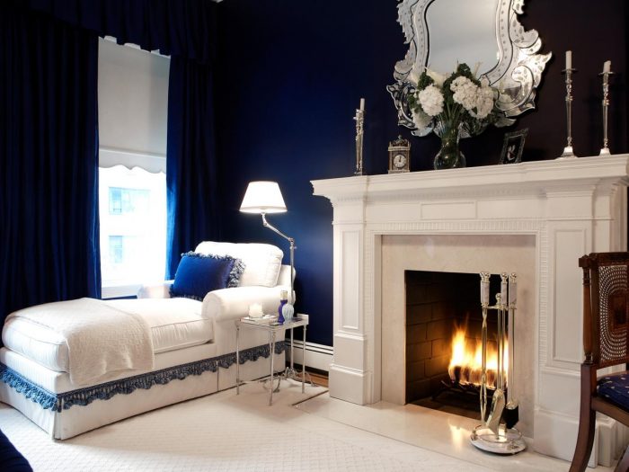 A denim blue bedroom with white furniture and a fireplace.