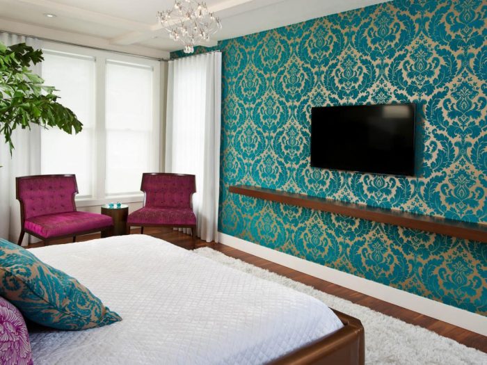 A bed in a bedroom with a TV on the textured wall.