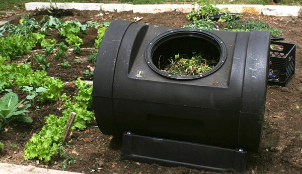 A black compost bin in a garden.