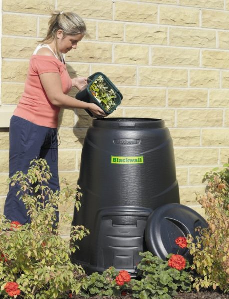 A woman beside a compost bin.