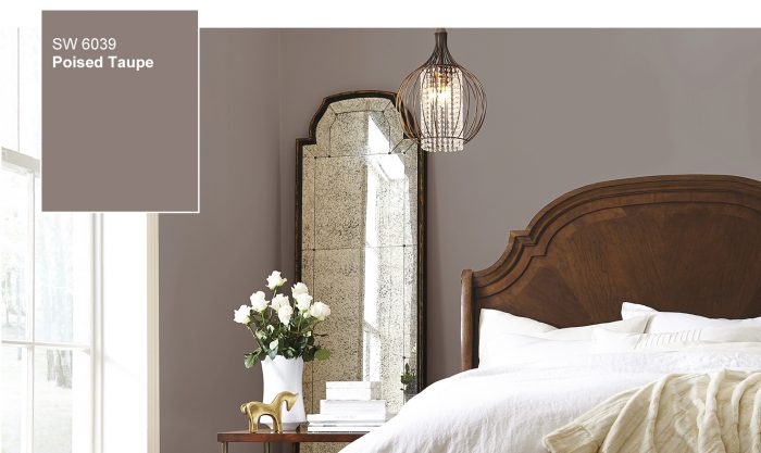 A poised taupe bedroom with a bed and a mirror.
