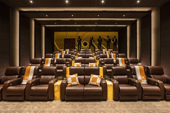 An opulent home theater with brown leather seats and gold accents in the luxurious residence at 924 Bel Air Rd.