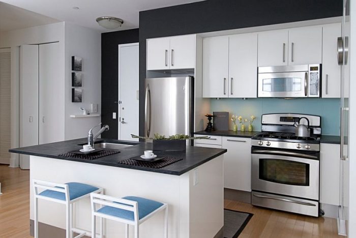 A black and white kitchen with a touch of blue adds a fun pop of color. Additionally, warm wood kitchen floors soften the look.