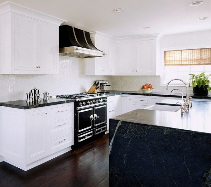 A black and white kitchen with marble counter tops and cabinets.