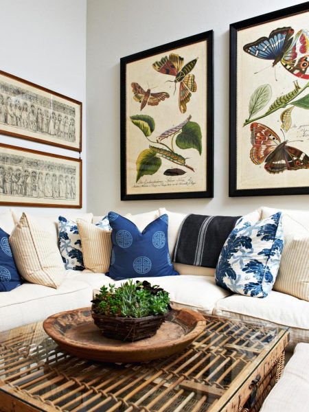 A living room with blue and white pillows and framed pictures, following the 2017 interior trends.