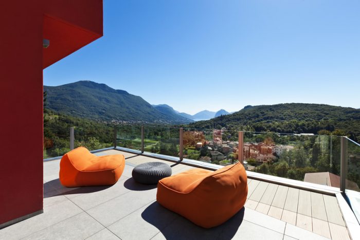 Two modern orange lounge chairs on a balcony overlooking the mountains.