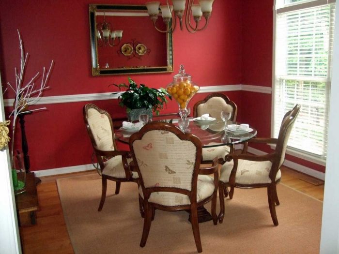 A modern dining room with red walls and furniture.