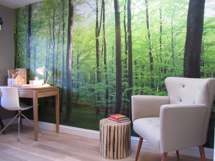 A bedroom with a biophilic design featuring a green forest mural on the wall.