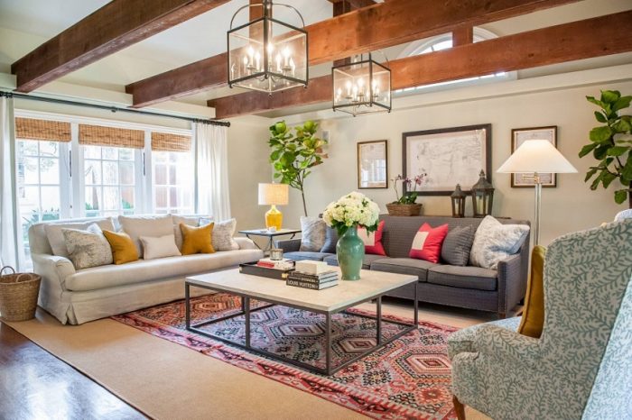 A living room with layered textures, wood beams and a rug.