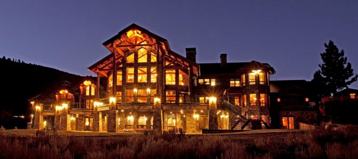 A large log cabin lit up at night.