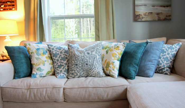 A white couch with a mixture of blue and white pillows.