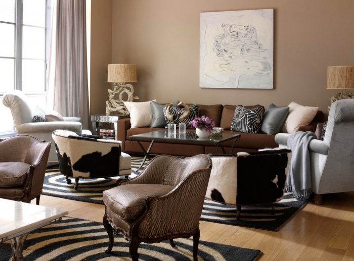 A living room with brown furniture and a cowhide rug that expertly mixes patterns.