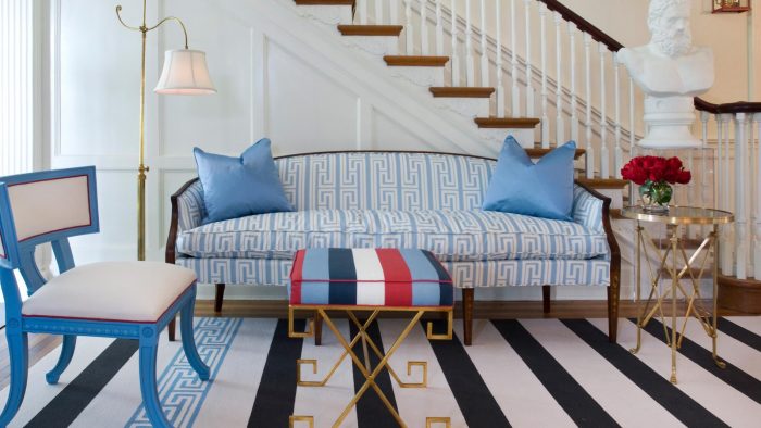 A living room with a blue couch and striped rug, featuring mixing patterns.