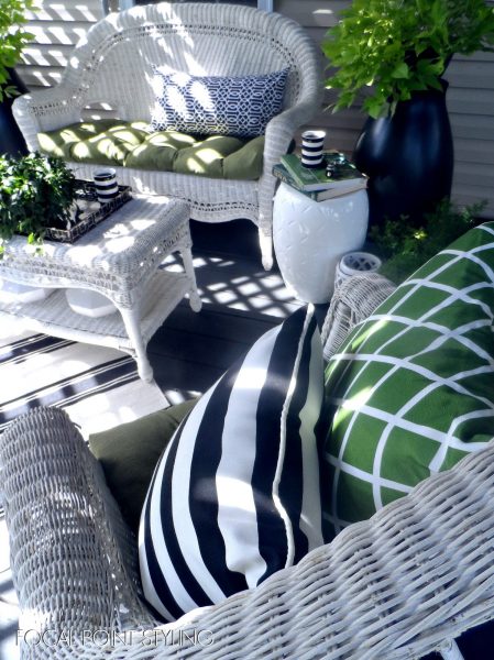 Wicker furniture on a porch with green and black pillows, showcasing mixing patterns.
