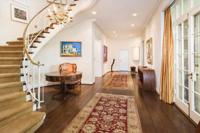 A hallway with a staircase and a rug in Taylor Swift's Home.
