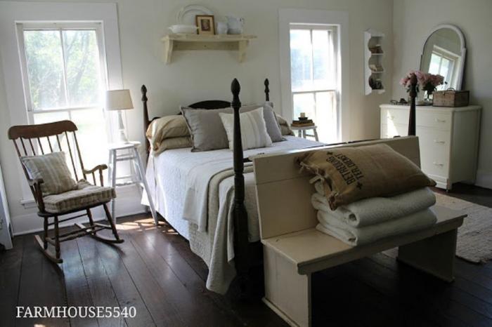 A white bedroom with wooden floors and a bed, featuring farmhouse touches.