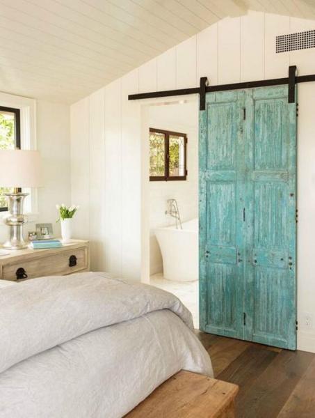 A pleasingly rustic bedroom with a blue barn door.