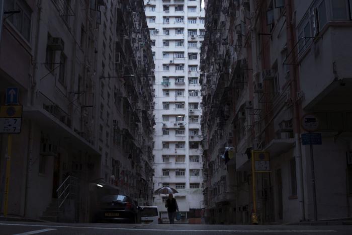 A person walking down a street with tall buildings in Hong Kong.