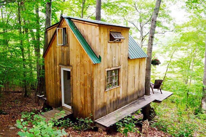 A small tree house sits in the middle of the woods showcasing top design and floor plan.