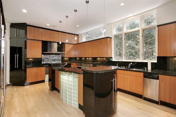A modern kitchen with wooden cabinets and black counter tops, following kitchen trends 2017.