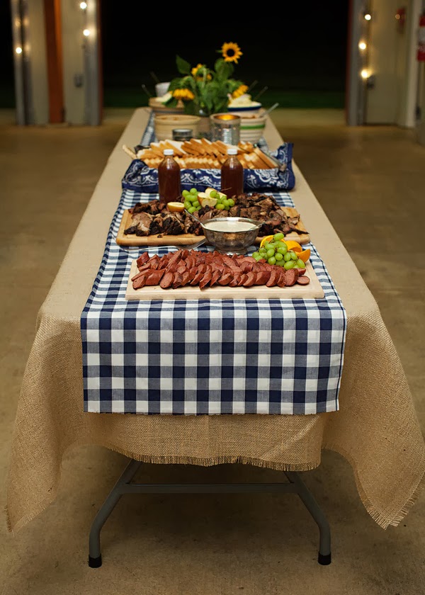 Backyard cookout decor featuring a long table with food and a checkered tablecloth.