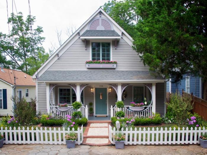 Exterior renovations of a small house with a white picket fence and flowers.