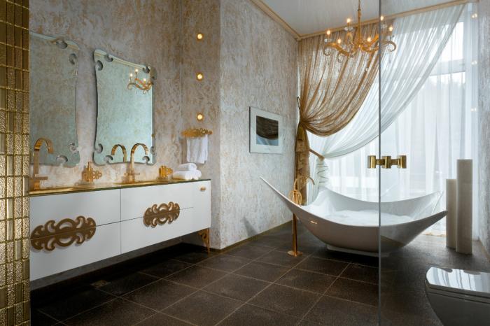 A lavishly decorated bathroom with a gold tub and a chandelier.
