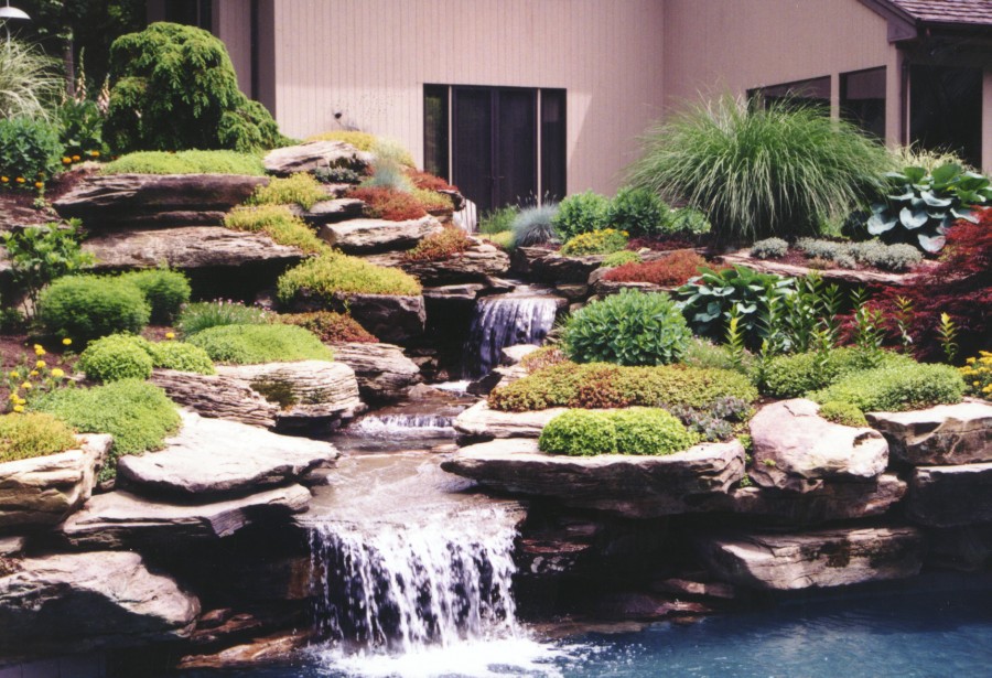 A backyard with a rock garden and waterfall.