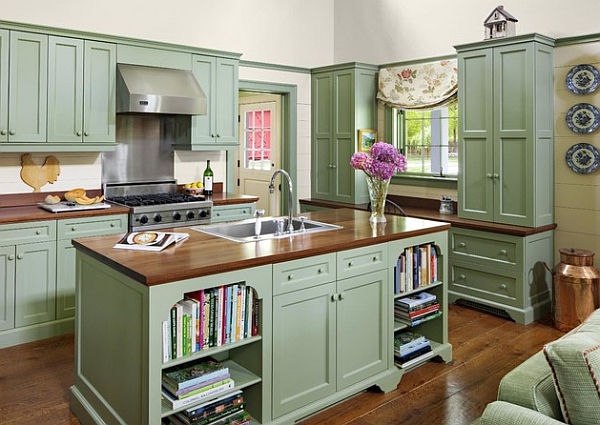 A trendy kitchen with green cabinets and wood floors.