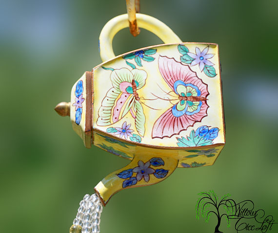 A yellow sun catcher teapot with butterflies on a chain.